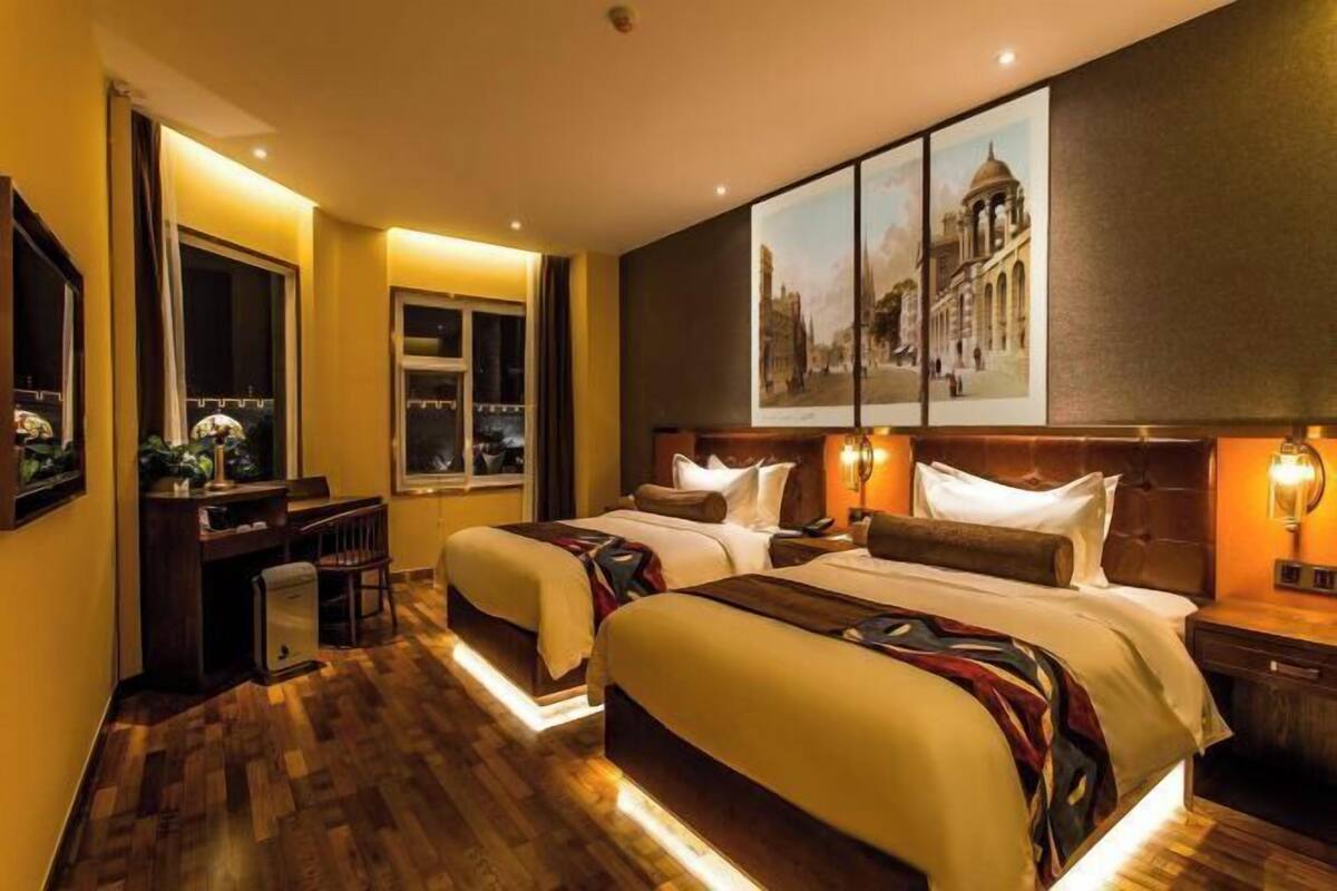 Een hotelkamer met twee bedden, een bureau en een groot schilderij aan de muur.