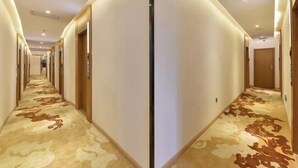Ένας διάδρομος ξενοδοχείου με δάπεδο καλυμμένο με χαλί και πόρτες και στις δύο πλευρές.