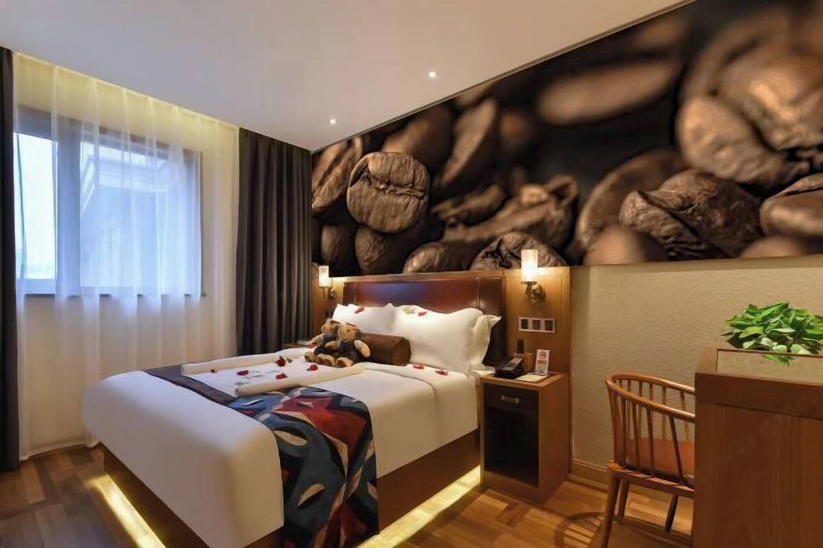 Een hotelkamer met een groot bed, een nachtkastje, een bureau en een muur met een wanddecoratie van koffiebonen.