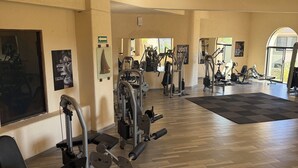 A gym with various exercise machines, wooden flooring, and motivational posters on the walls.
