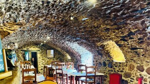 A rustic interior with stone walls, a yellow sofa, wooden tables, and red chairs. - Chateau du rey Restaurant L'Abeuradou (Saint-Andre-de-Majencoules)