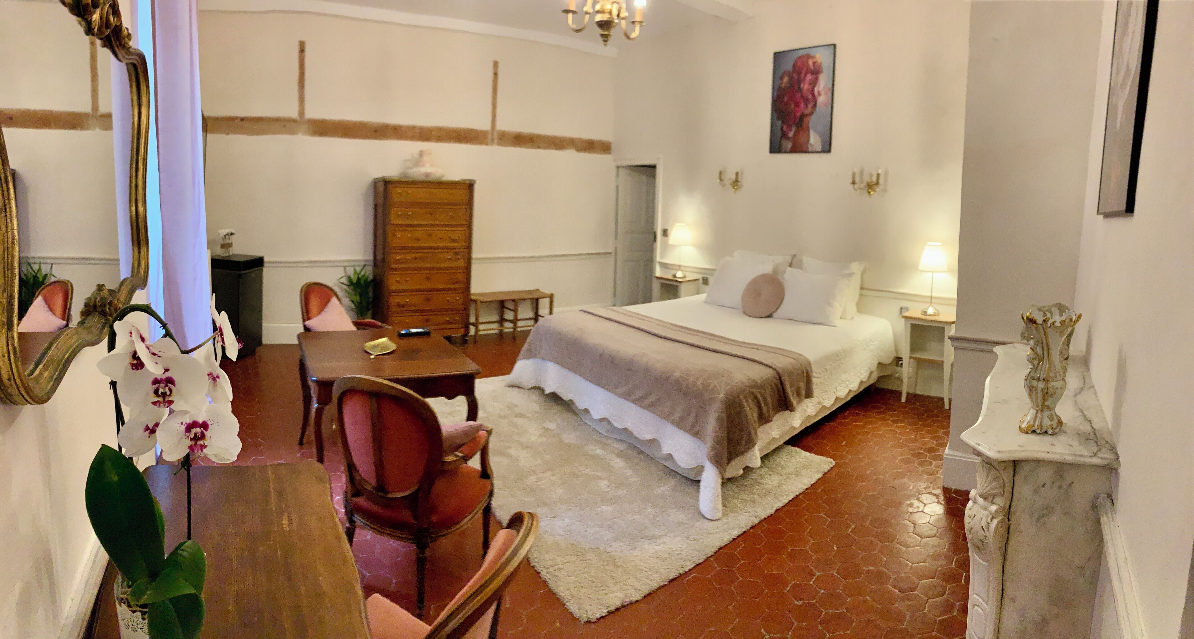 A hotel room with a bed, a desk, a chair, a dresser, and a mirror.