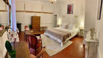 A hotel room with a bed, a desk, a chair, a dresser, and a mirror.