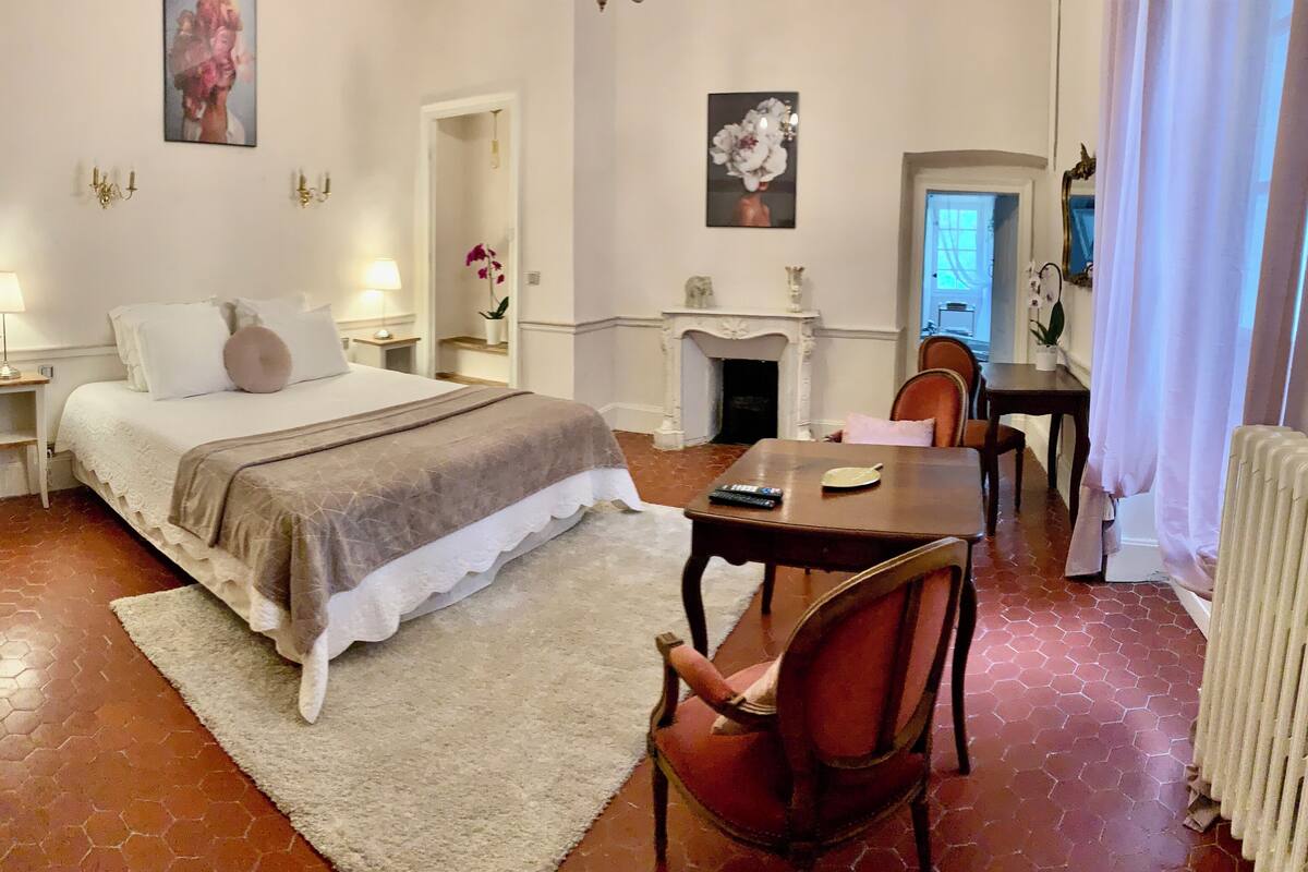 Une chambre d’hôtel comprenant un lit, des tables de chevet, un bureau, une chaise, une cheminée et un radiateur.