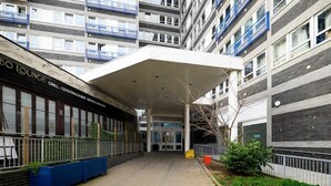 Un edificio con acceso cubierto, un bar llamado “BO LOUNGE GRILL” a la izquierda y una entrada “VISTA” en el centro.