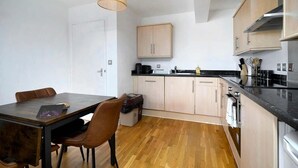 Una cocina compacta con armarios de madera, una mesa de comedor con sillas y una lámpara colgante.