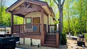 A cabin with a porch, a truck, and a bear statue. - Dudley Creek RV Resort (Gatlinburg)