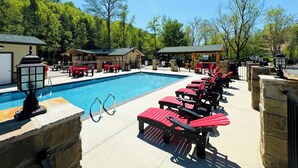 A swimming pool with red lounge chairs and stone walls. - Dudley Creek RV Resort (Gatlinburg)