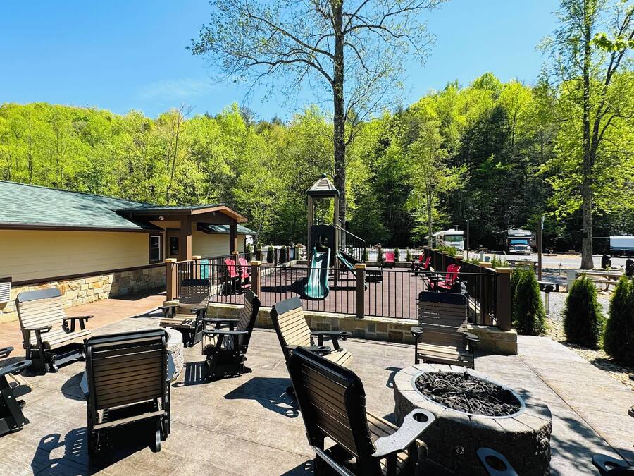 An outdoor patio area with seating and a fire pit, surrounded by trees and a building with a green roof.