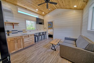 Una cabaña compacta y moderna con cocina, comedor y un espacio de descanso acogedor.