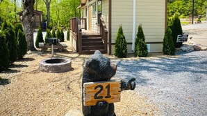 A small cabin with a porch, surrounded by trees and a gravel driveway. - Dudley Creek RV Resort (Gatlinburg)