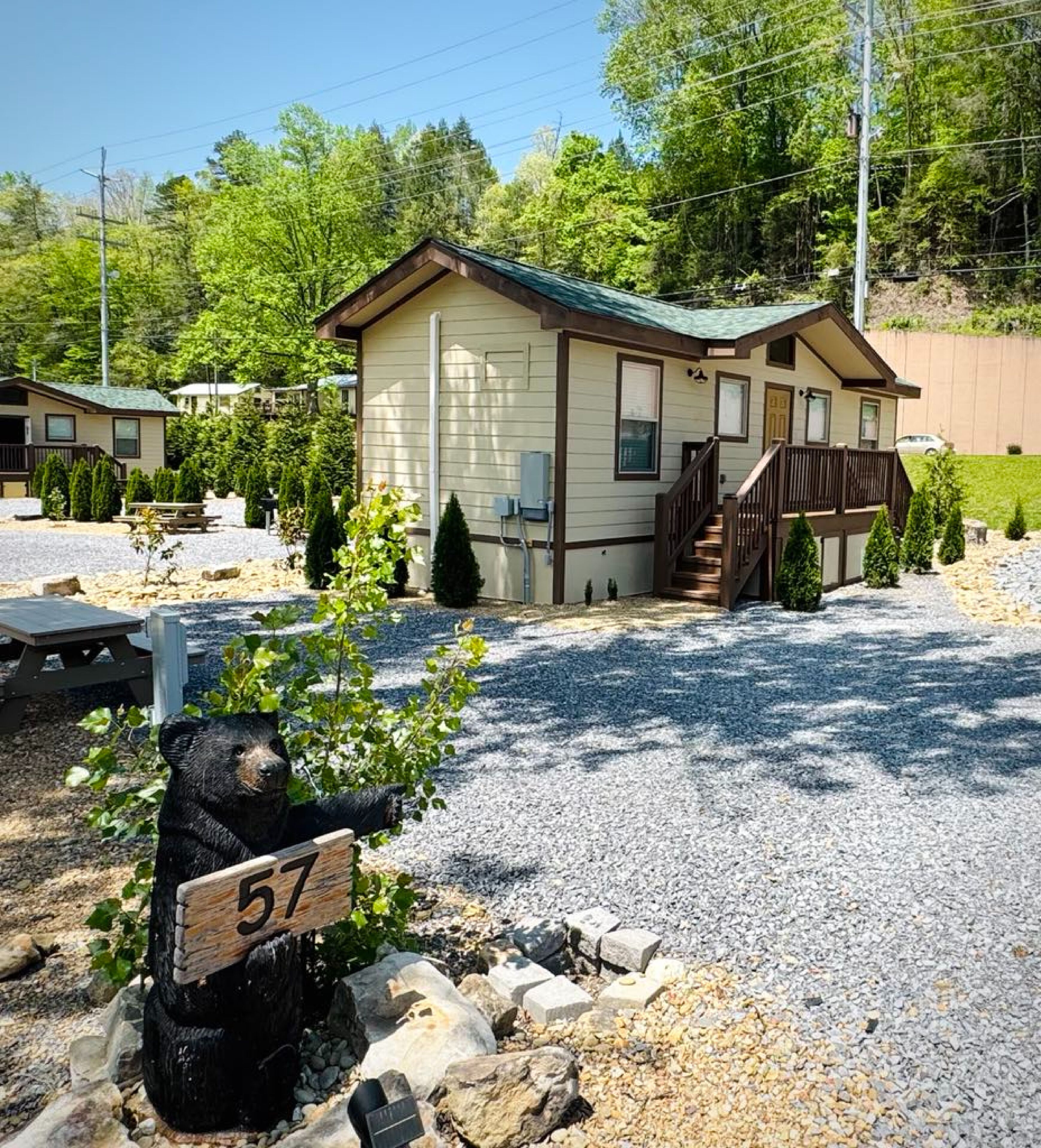 A lodge with a covered porch, a picnic table, and a bear statue.