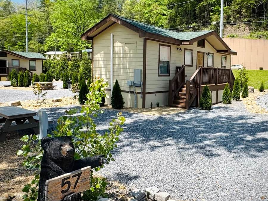 A lodge with a covered porch, a picnic table, and a bear statue.