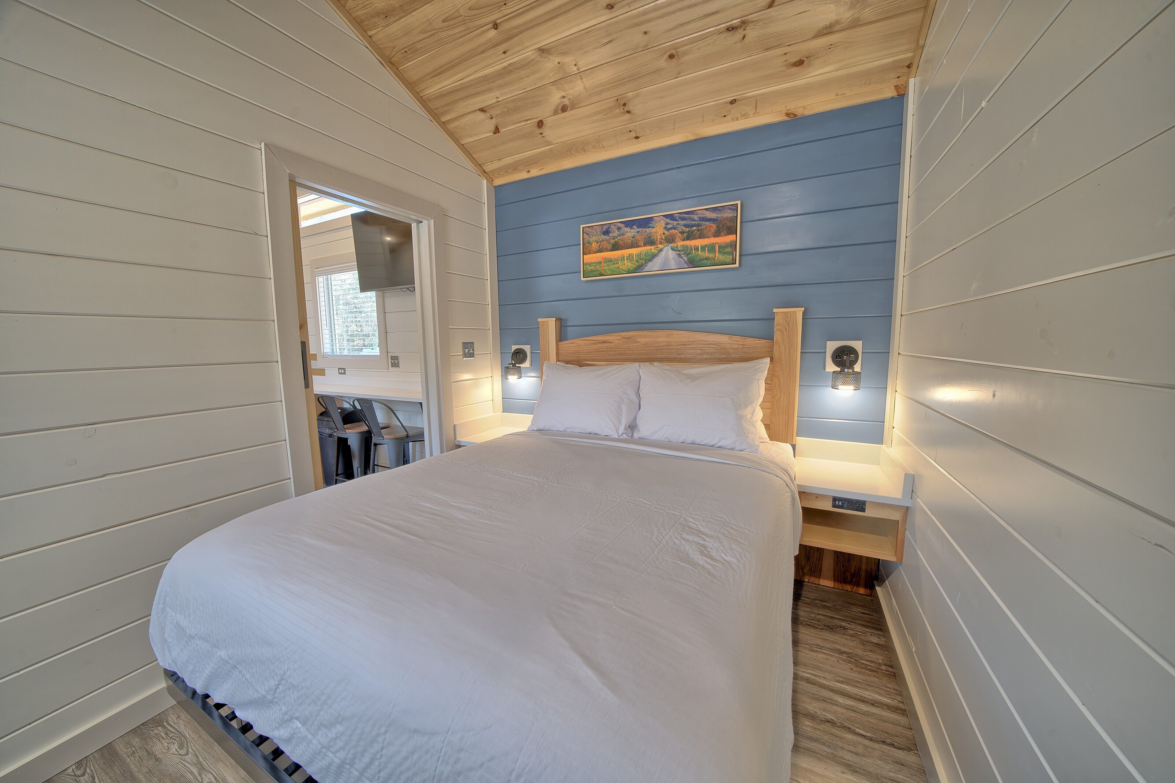 Une chambre avec un grand lit, un plafond en bois et un tableau accroché au mur.