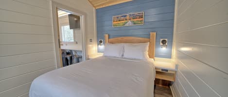 Une chambre avec un grand lit, un plafond en bois et un tableau accroché au mur.