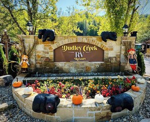 Dudley Creek RV Resort entrance with stone walls, bear sculptures, and a sign.