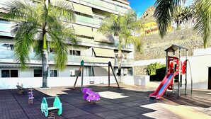 Uma área de lazer ao ar livre com balanços, escorrega e equipamentos de ginástica.