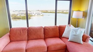 A room with a large window, a pink sofa, a striped rug, and a lamp. - New Listing - Penthouse at Sea Club - Sunrise & Sunset Retreat  #501 (Indian Shores)