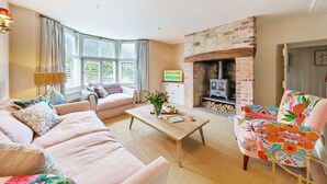 Una sala de estar con sofá, sillón, mesa de centro y chimenea.