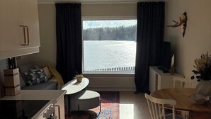 A modern kitchen with a dining area, a large window with a view of a lake, and a ceiling with horizontal lines. - Waterfront Guesthouse with Private Dock & Rowboat (Västra Götalands län)