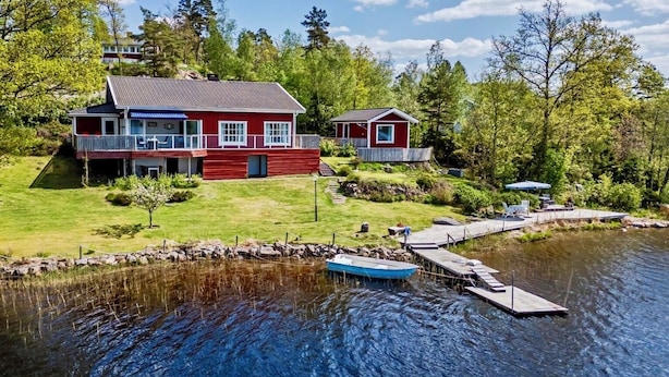 A lakeside cabin with a dock, a boat, and a well-maintained lawn. - Waterfront Guesthouse with Private Dock & Rowboat (Västra Götalands län)