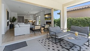 A modern living room with a sofa, coffee table, and chairs. There is a fireplace and a view of the outdoors. - The Platinum House!  PGA Signature (Walk to Ernies, Stadium Course!) (La Quinta)