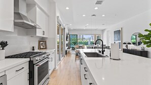 A modern kitchen with white cabinetry, a large island, and a view to the outdoors. - The Platinum House!  PGA Signature (Walk to Ernies, Stadium Course!) (La Quinta)