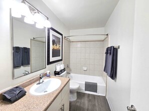 Ein Badezimmer mit Waschbecken, Spiegel, Handtuchhalter, Toilette und Badewanne.