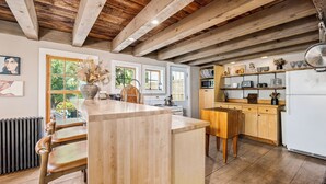 A kitchen with a wooden island, wooden cabinets, and a view of the outdoors. - Union Street Cottage - Built in 1900 (Hudson)