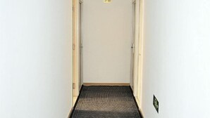 A narrow hallway with a patterned carpet leading to a door with a sign above it. - Apple Inn Express Hotel (Huantai)