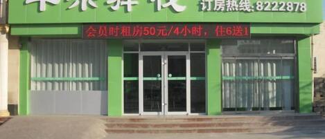 Un hotel con fachada verde y un letrero con caracteres chinos.