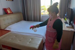 Habitación de hotel con una cama, mesita de noche, ventana con cortinas y escritorio con computadora y auriculares.