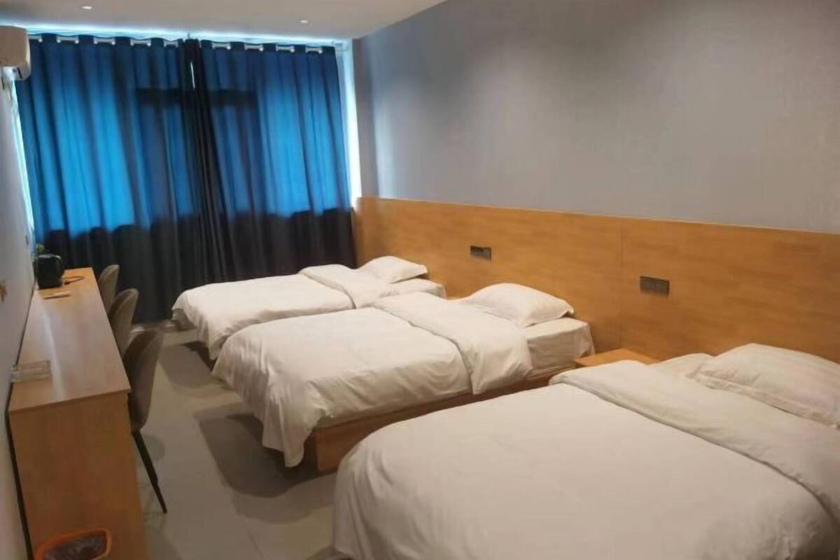 A hotel room with three beds, a desk, and a chair.