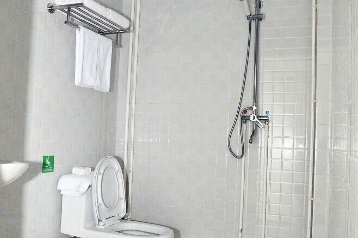 A bathroom with a toilet, a shower, and a towel rack.