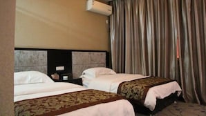 Hotellihuone, jossa on kaksi sänkyä, sängynpääty, ilmastointilaite ja verho.