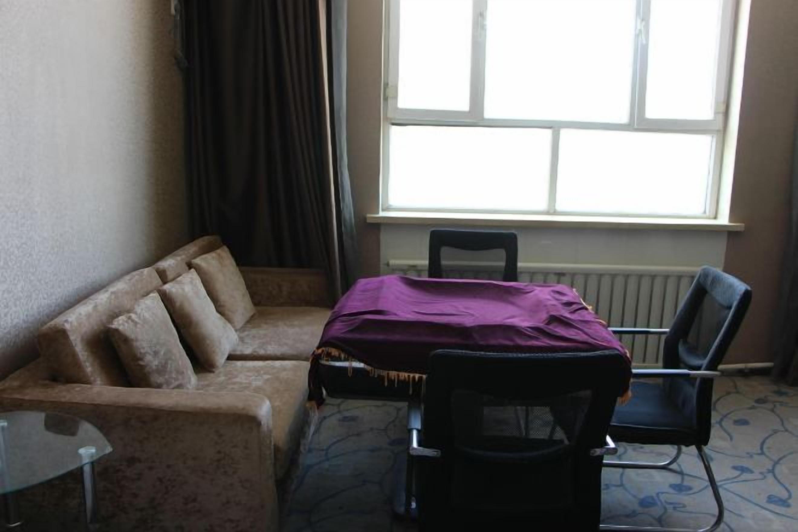 A room with a sofa, a chair, a table, and a window.