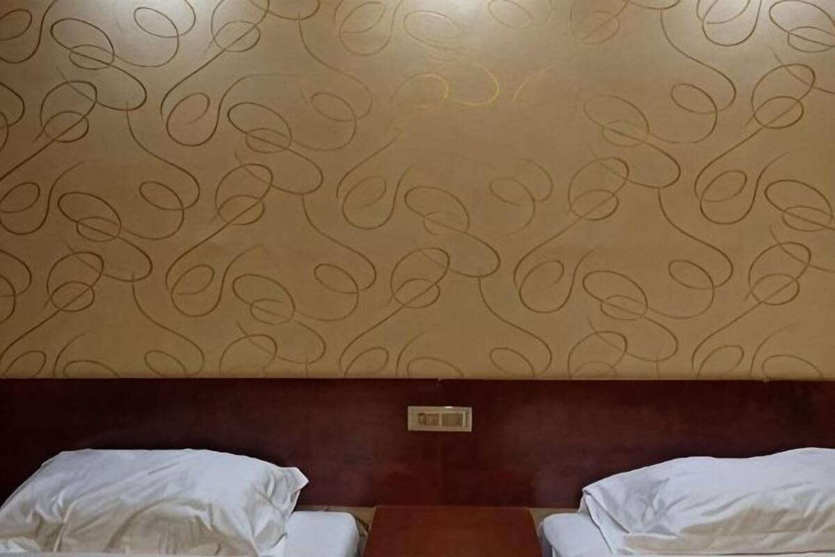 A hotel room with two beds, a wooden headboard, and a patterned wall.