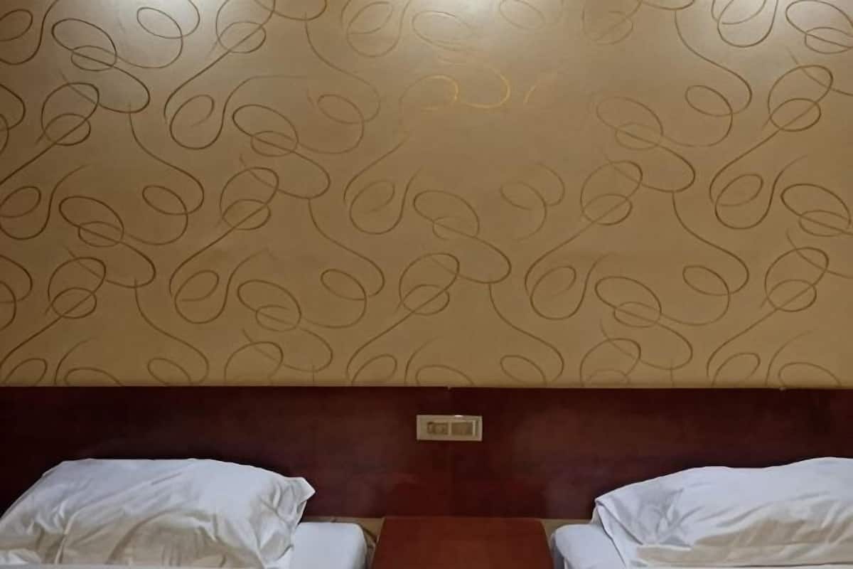 A hotel room with two beds, a wooden headboard, and a patterned wall.