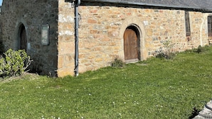 A stone church with a bell tower, arched door, and a tiled roof.