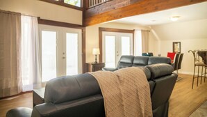 Una sala de estar con un sofá, un comedor con una mesa y sillas, y una escalera.