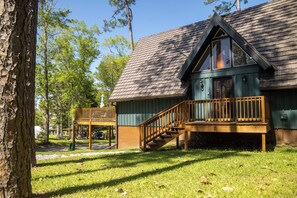 Une cabane en bois dotée d’un balcon et d’un escalier menant à une terrasse.