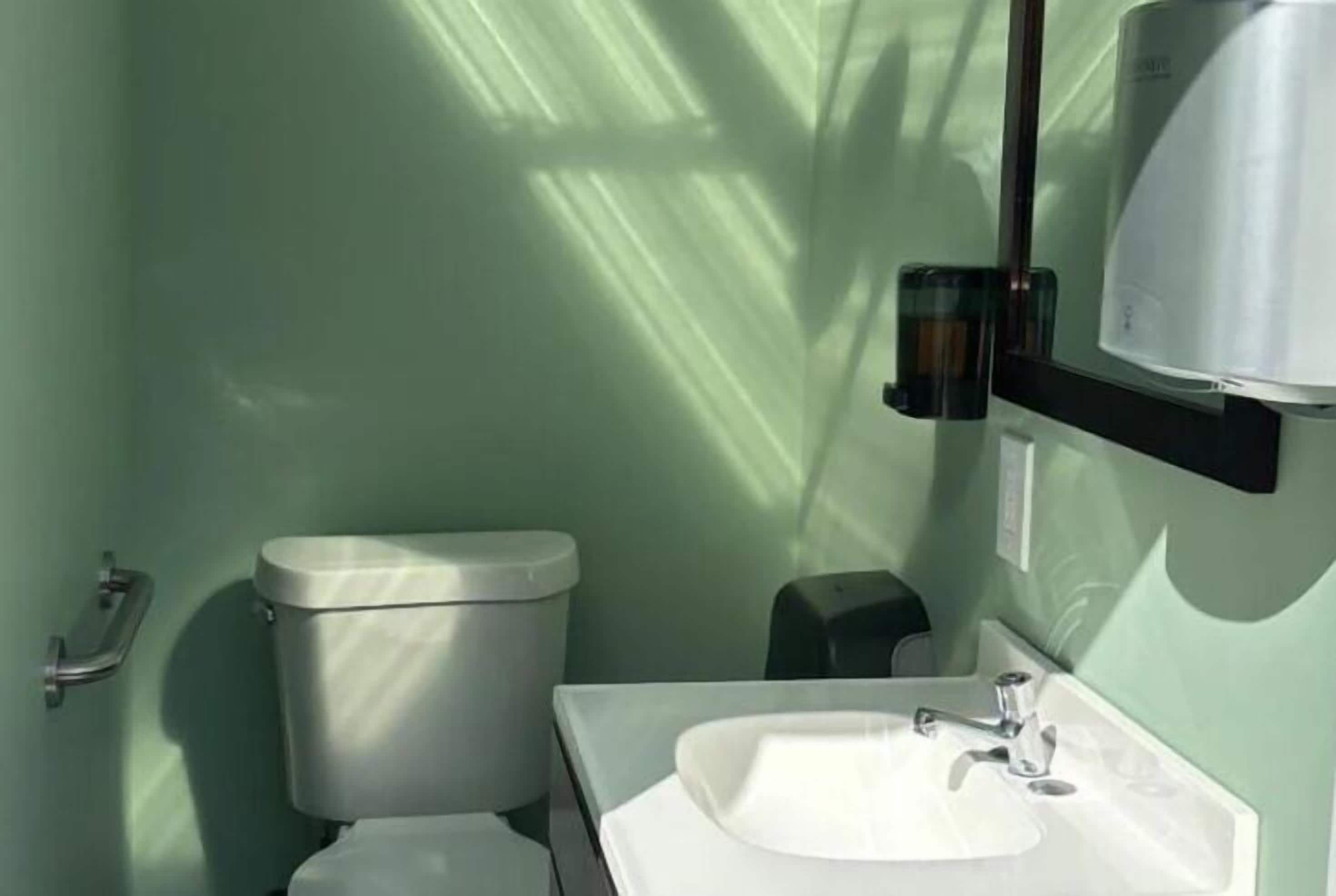 Kylpyhuone, jossa on wc, pesuallas ja käsienkuivaaja.