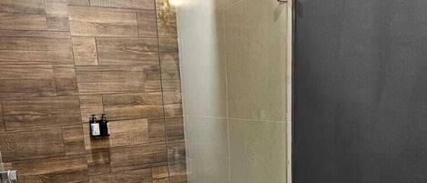 A modern bathroom with a glass shower enclosure, a toilet, and a bidet.