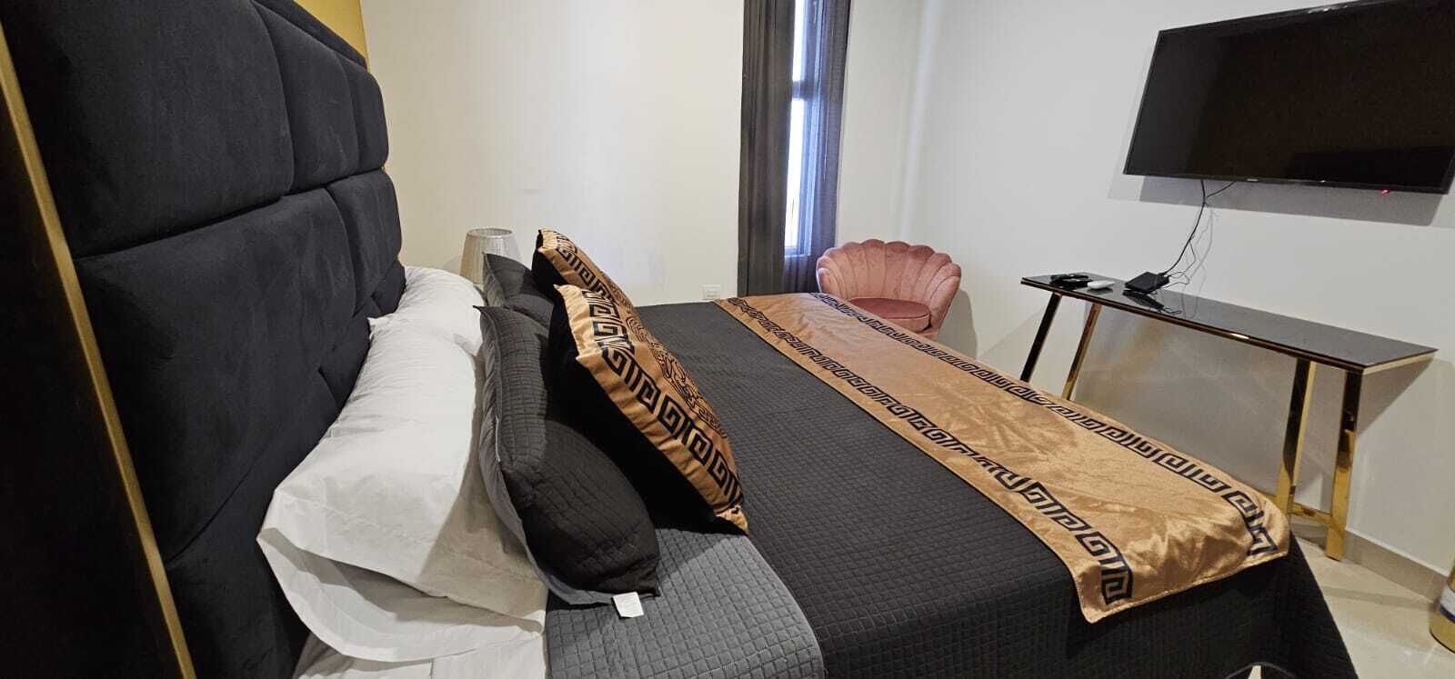 A hotel room with a large bed, a television, a small table, and a chair.