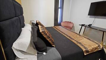 A hotel room with a large bed, a television, a small table, and a chair.