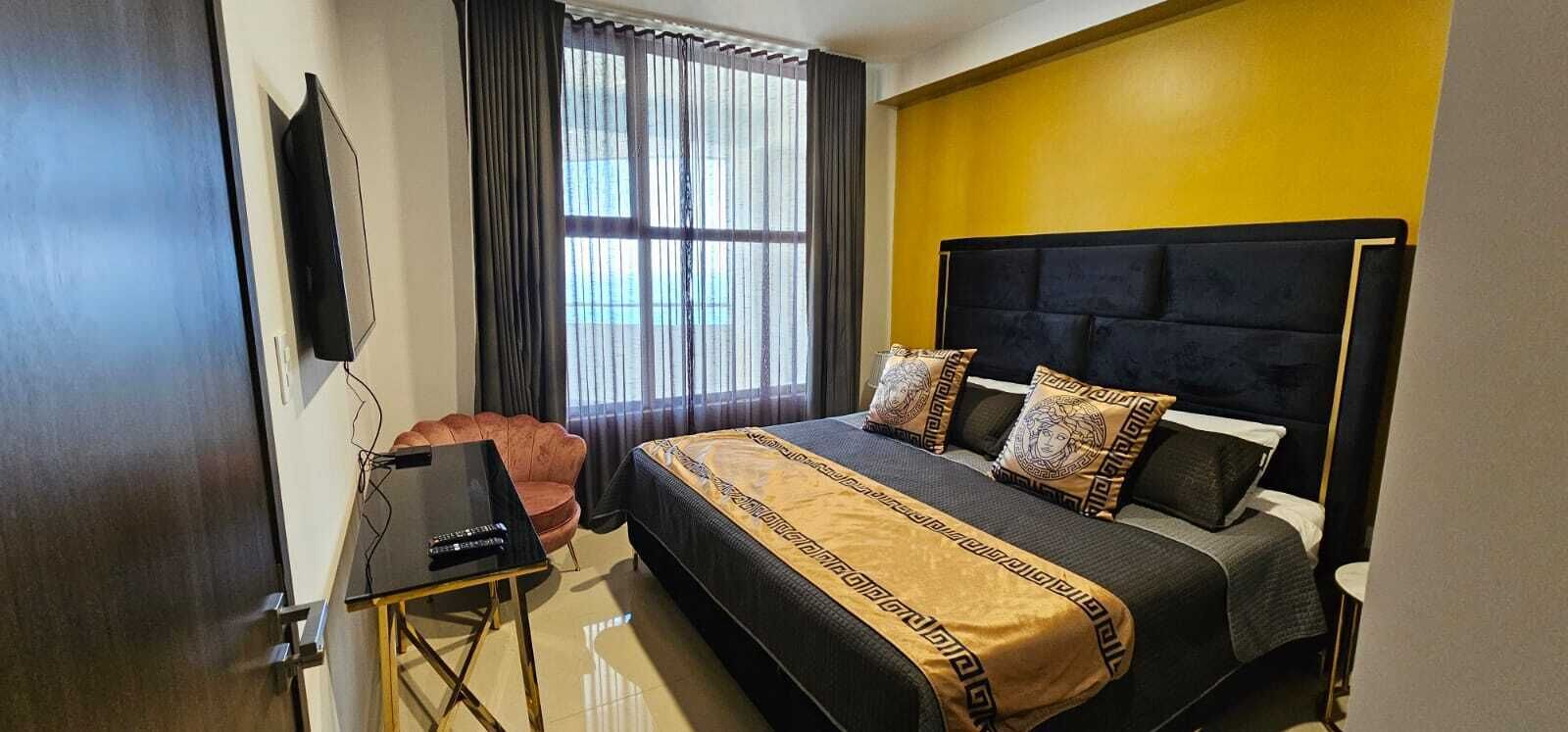 Una habitación de hotel con cama, escritorio, silla y televisión.