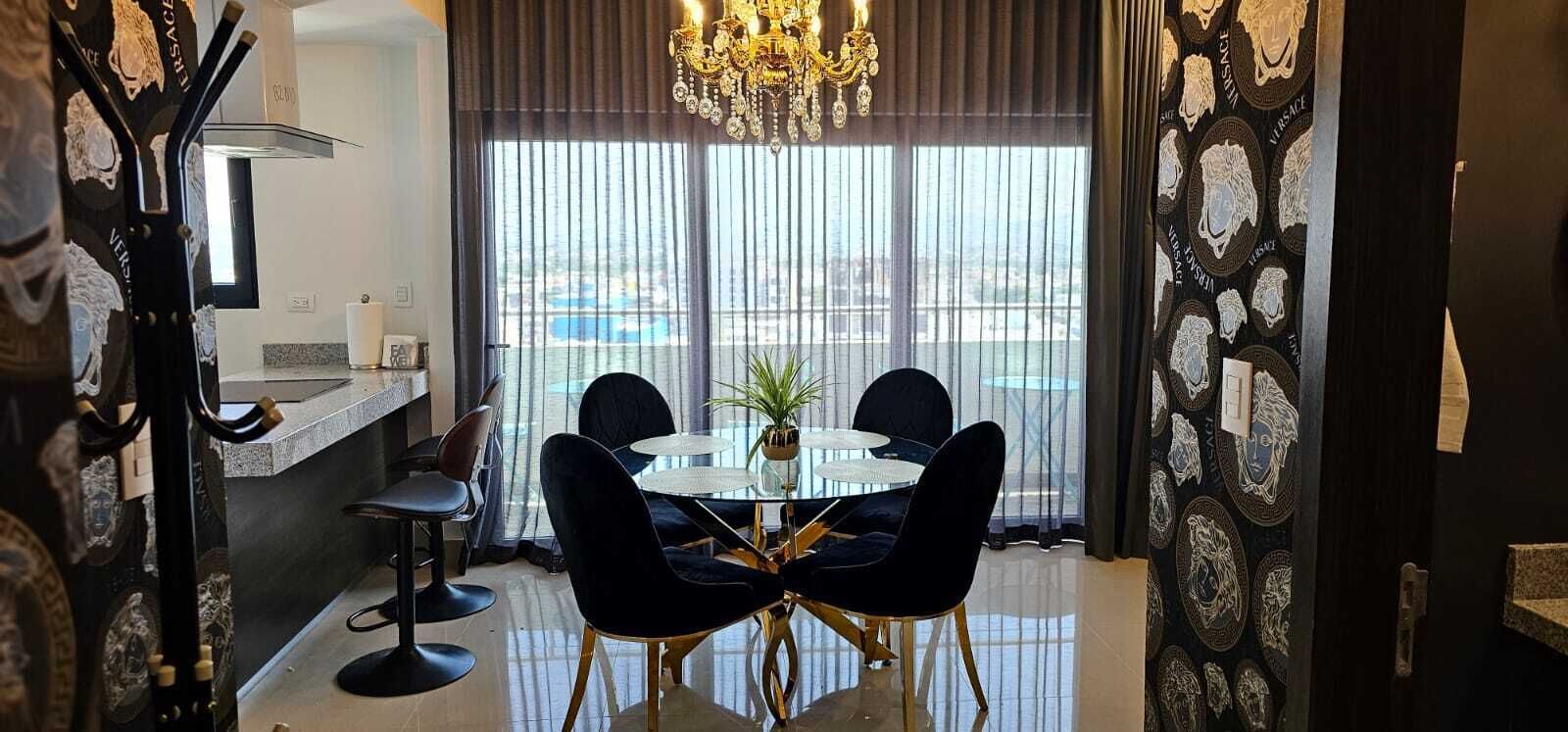 A dining area with a round table, black chairs, and a chandelier.