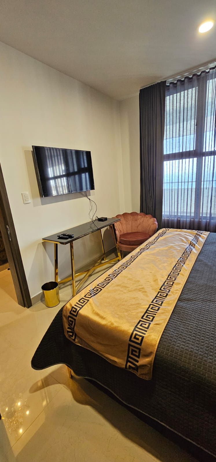 Hotelkamer met een bed, bureau, stoel, televisie en raam met gordijnen.