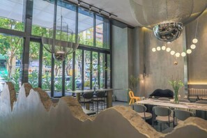 A modern dining area with large windows, a chandelier, and a table with chairs. - Duoman Hotel (Dongguan Xiping Metro Station) (Dongguan)