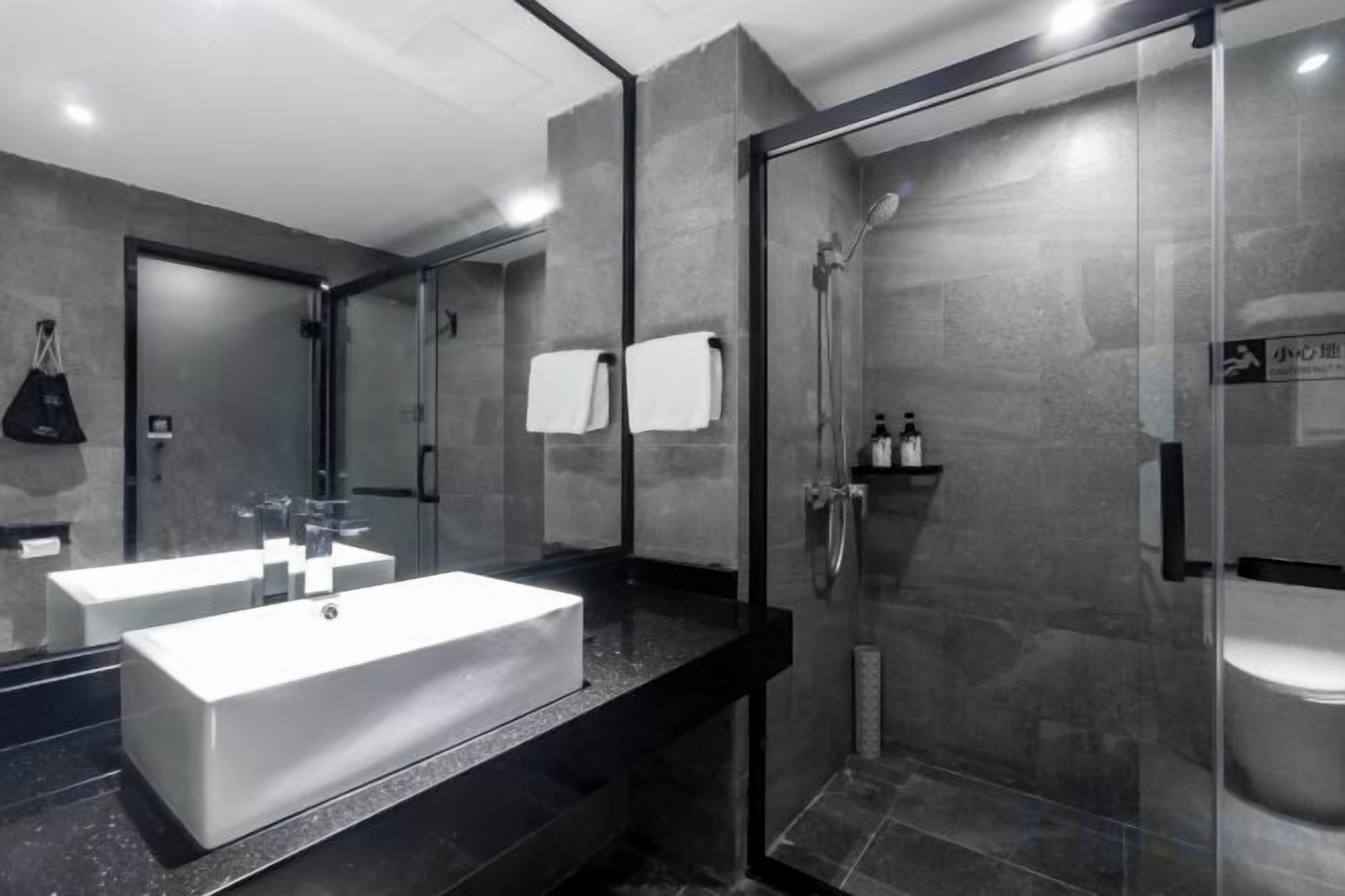 A modern bathroom with a large mirror, two sinks, and a glass-enclosed shower.